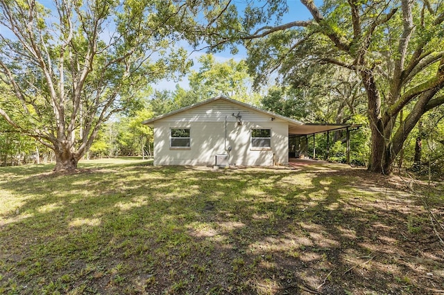 exterior space with a carport and a lawn