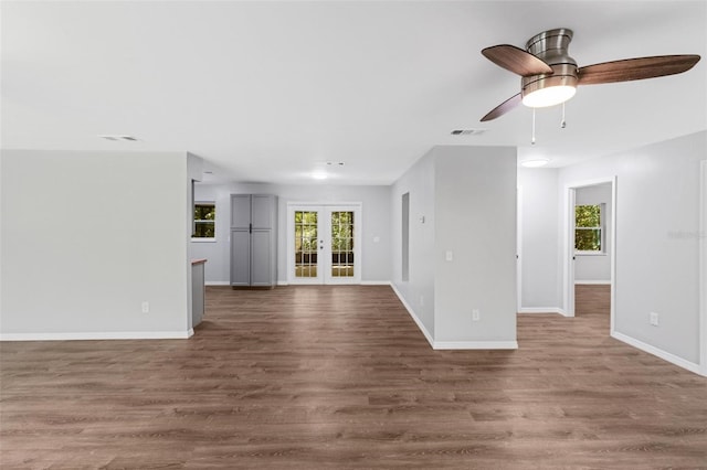 unfurnished living room with ceiling fan, plenty of natural light, wood-type flooring, and french doors