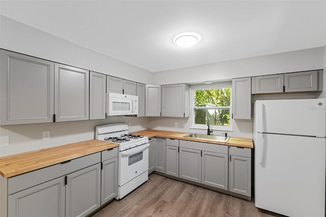 kitchen featuring butcher block countertops, gray cabinets, sink, and white appliances