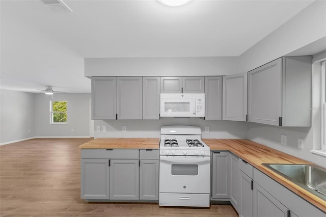 kitchen featuring gray cabinetry, white appliances, sink, and wooden counters