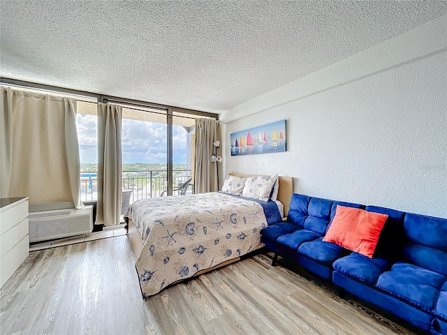 bedroom with a textured ceiling, access to exterior, and light hardwood / wood-style floors