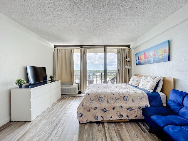 bedroom featuring light hardwood / wood-style floors, access to outside, and a textured ceiling