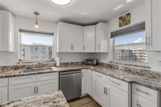 kitchen with white cabinets, wood finished floors, stainless steel dishwasher, pendant lighting, and a sink