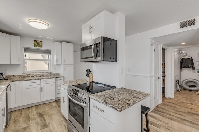 kitchen with stainless steel appliances, visible vents, and white cabinetry