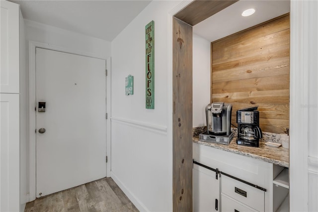 doorway to outside featuring light wood-style floors and wooden walls