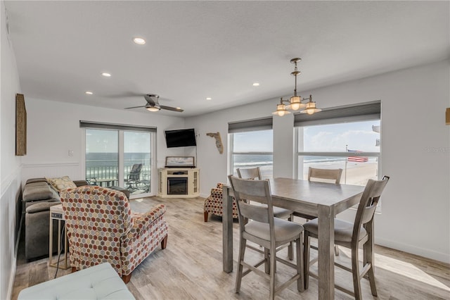 dining room with a glass covered fireplace, wainscoting, light wood finished floors, and recessed lighting