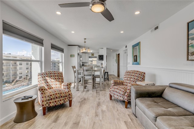 living area with a wainscoted wall, light wood-type flooring, visible vents, and recessed lighting