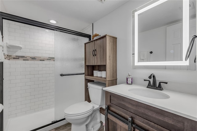 bathroom with toilet, a shower stall, and vanity