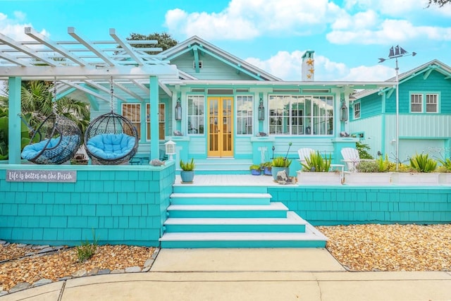 back of property with french doors, a chimney, and a pergola