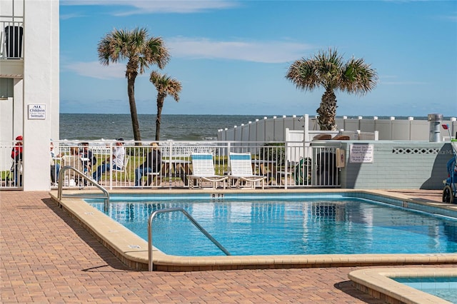 view of pool featuring a water view and a patio area