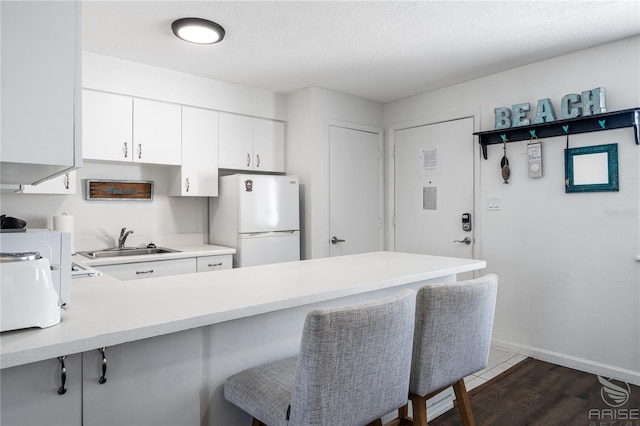 kitchen with a breakfast bar area, kitchen peninsula, sink, and white fridge