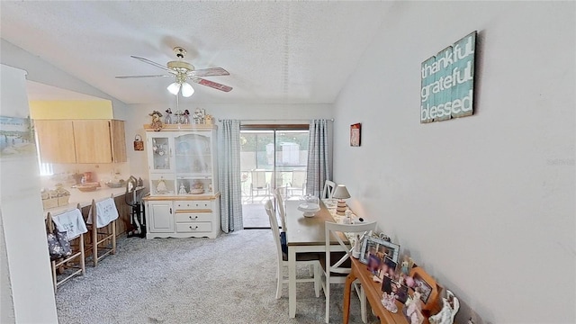 carpeted dining area featuring a textured ceiling, ceiling fan, and vaulted ceiling