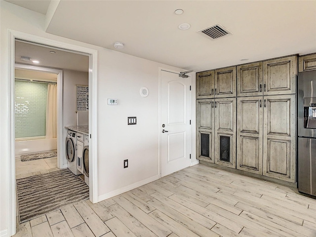 interior space featuring light wood-type flooring, stainless steel fridge with ice dispenser, and independent washer and dryer