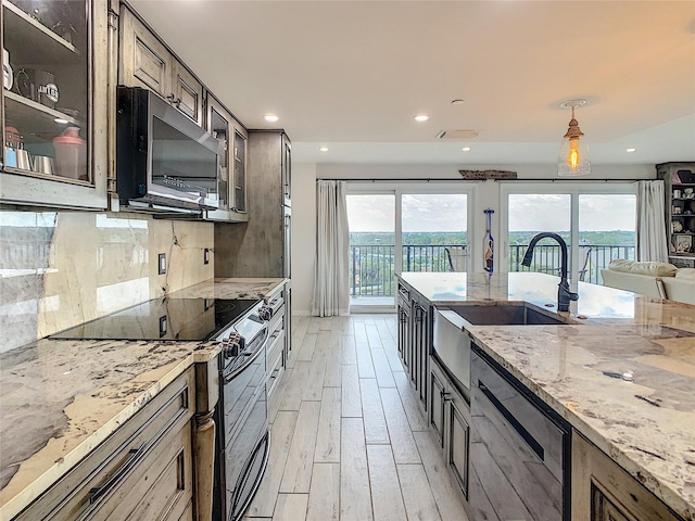 kitchen with hanging light fixtures, backsplash, light stone countertops, electric range, and light hardwood / wood-style floors