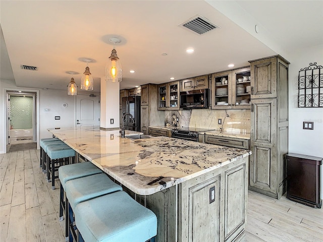 kitchen featuring light hardwood / wood-style flooring, hanging light fixtures, a kitchen breakfast bar, and a large island