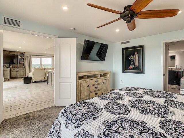 bedroom with ceiling fan, connected bathroom, and light hardwood / wood-style floors