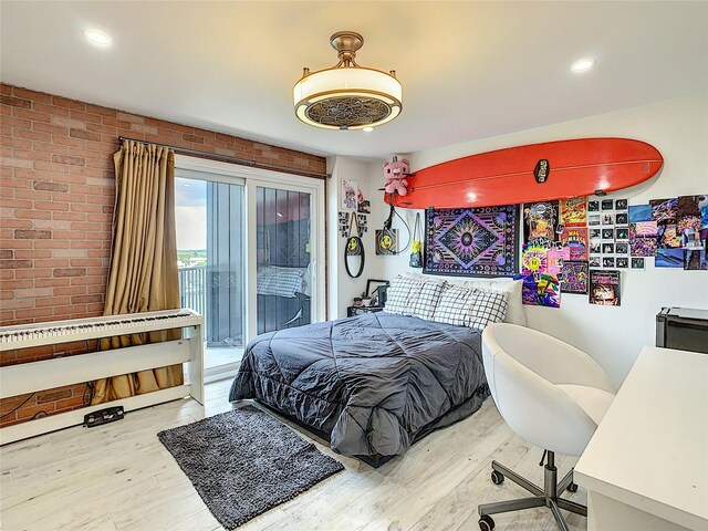 bedroom featuring light wood-type flooring, access to outside, and brick wall