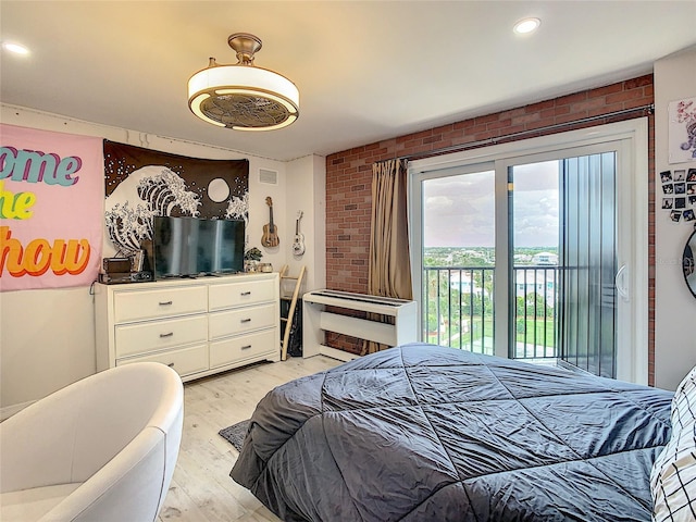 bedroom with brick wall, access to exterior, light wood-type flooring, and heating unit