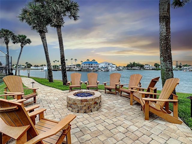 patio terrace at dusk with a fire pit and a water view