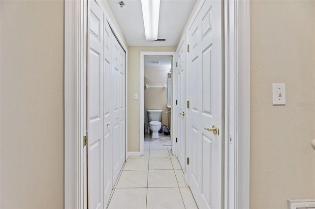 hall featuring a textured ceiling and light tile patterned floors