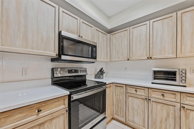 kitchen featuring appliances with stainless steel finishes, light brown cabinets, and backsplash