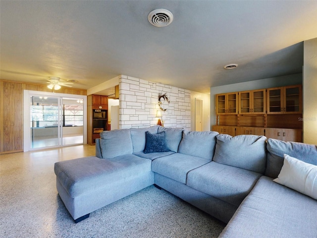 living room with ceiling fan and wooden walls