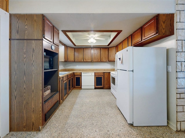 kitchen featuring a tray ceiling, white appliances, and ceiling fan