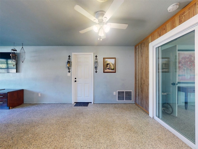 interior space with wood walls and ceiling fan