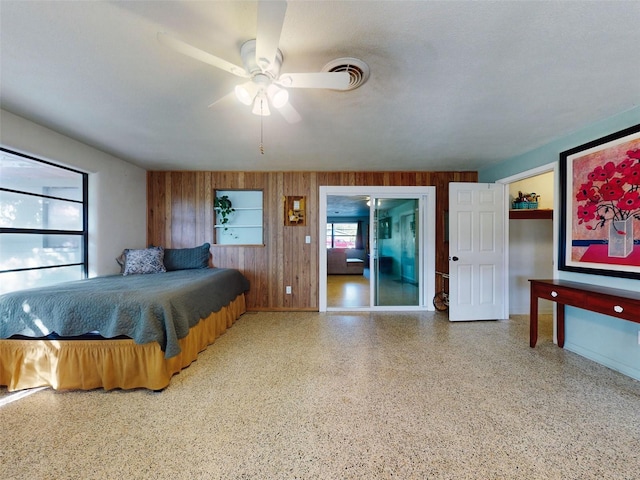 bedroom with ceiling fan and wooden walls