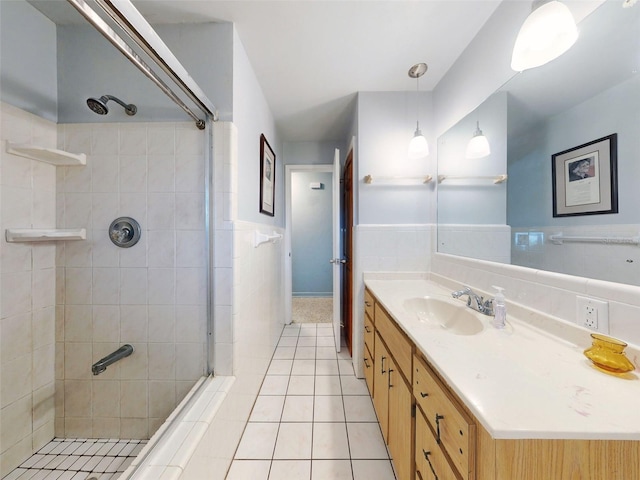 bathroom featuring vanity, tile walls, tile patterned floors, and a tile shower