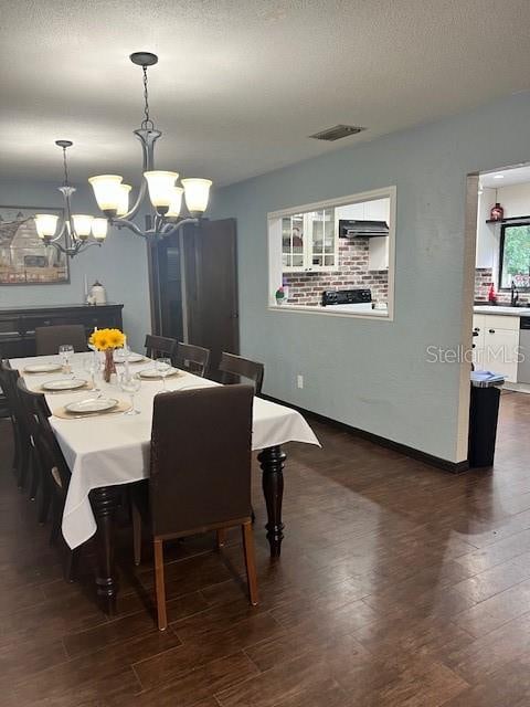 dining room featuring sink, dark hardwood / wood-style flooring, a notable chandelier, and a textured ceiling