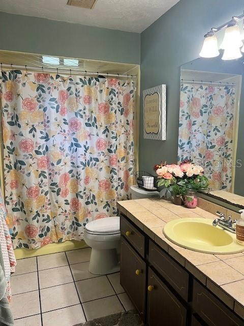 bathroom featuring toilet, tile patterned floors, vanity, a textured ceiling, and a shower with shower curtain