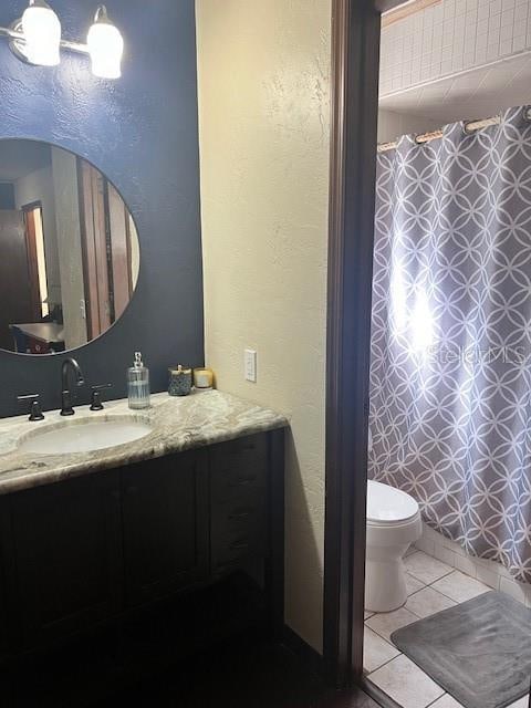 bathroom with tile patterned flooring, vanity, toilet, and walk in shower