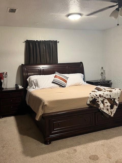 bedroom with a textured ceiling, ceiling fan, and carpet floors