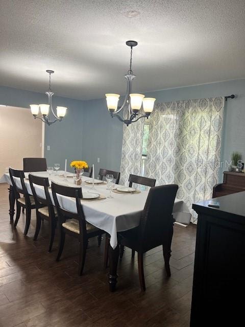 dining room with dark wood-type flooring, an inviting chandelier, and a textured ceiling