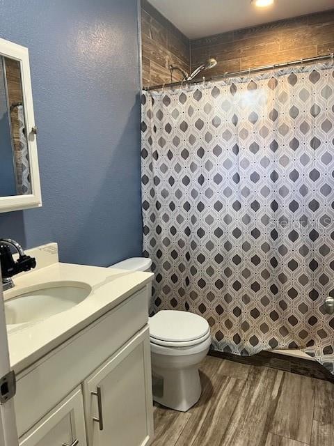 bathroom featuring hardwood / wood-style floors, a shower with curtain, toilet, and vanity