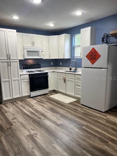 kitchen featuring dark wood-type flooring, sink, white appliances, and white cabinets