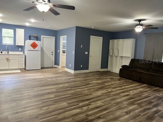 living room featuring ceiling fan, dark hardwood / wood-style floors, and sink