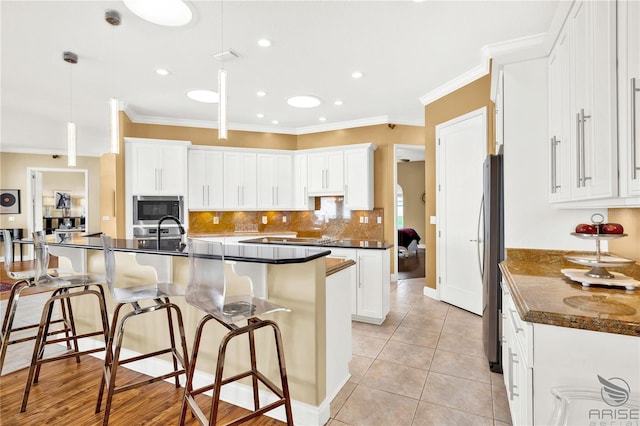 kitchen with pendant lighting, white cabinets, light tile patterned floors, appliances with stainless steel finishes, and crown molding