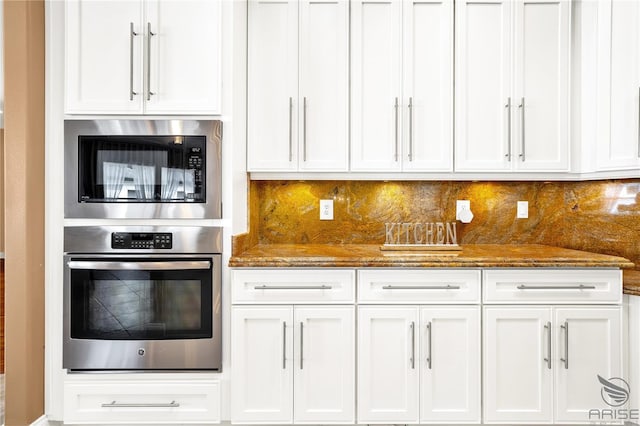 kitchen featuring white cabinets, stainless steel appliances, and dark stone countertops