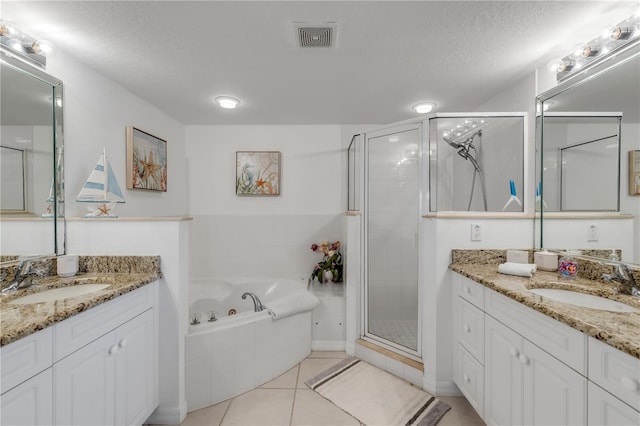 bathroom with a textured ceiling, vanity, tile patterned floors, and plus walk in shower