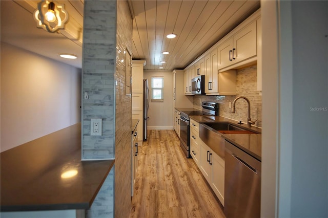 kitchen with backsplash, light hardwood / wood-style flooring, stainless steel appliances, white cabinetry, and sink