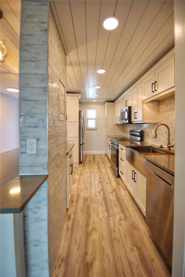 kitchen with appliances with stainless steel finishes, white cabinetry, light hardwood / wood-style flooring, and sink