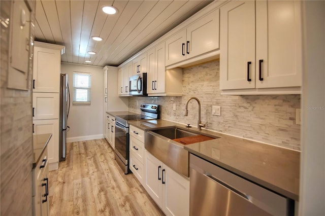 kitchen featuring backsplash, appliances with stainless steel finishes, light hardwood / wood-style floors, sink, and white cabinetry