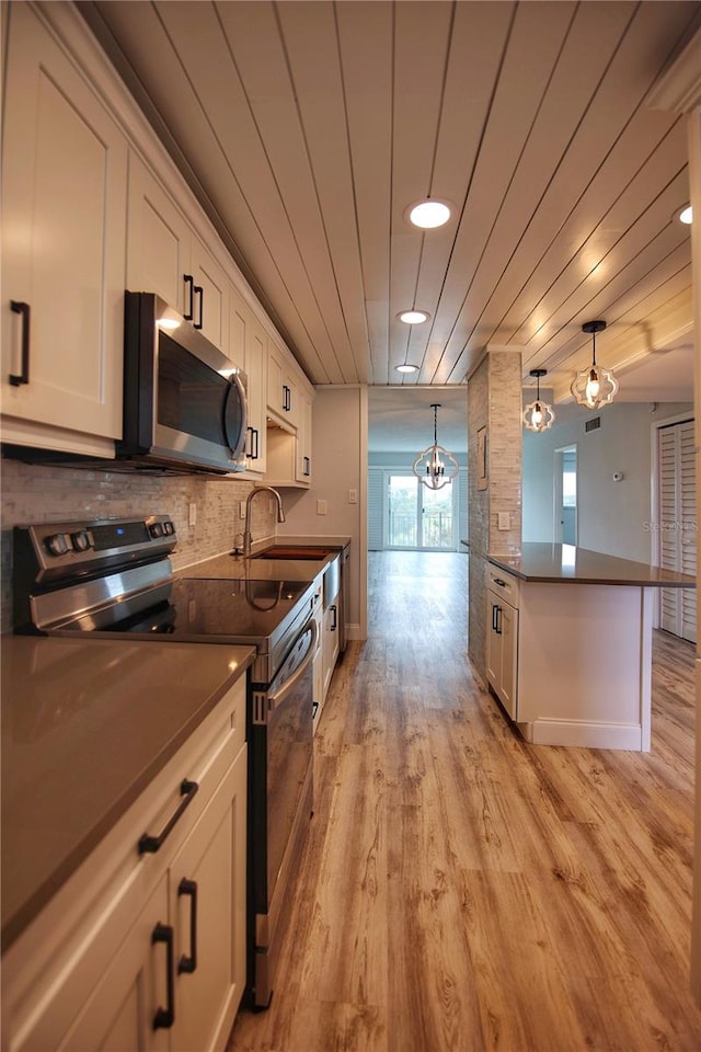 kitchen featuring light hardwood / wood-style floors, stainless steel appliances, white cabinets, and hanging light fixtures