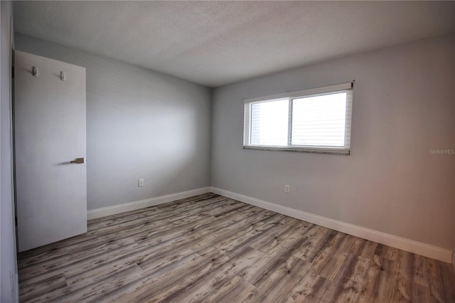 unfurnished room featuring wood-type flooring and a textured ceiling