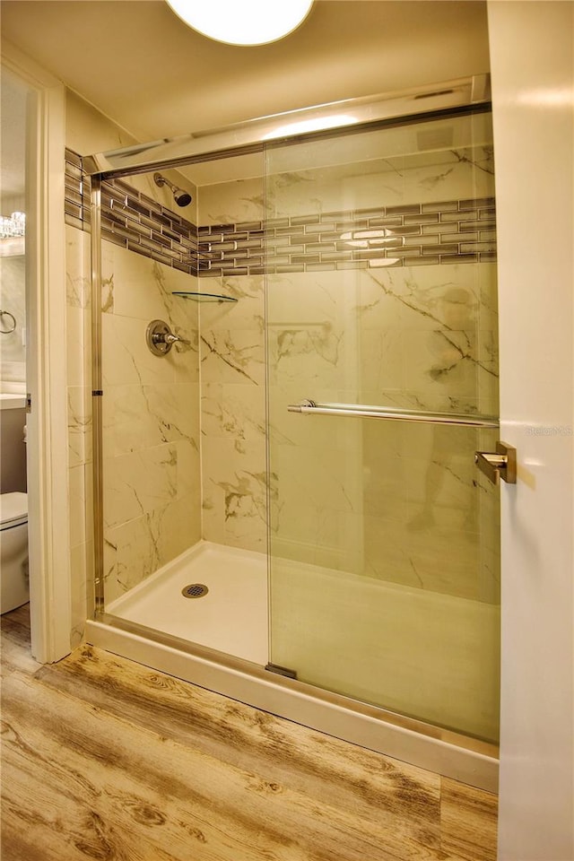 bathroom with toilet, an enclosed shower, and hardwood / wood-style flooring