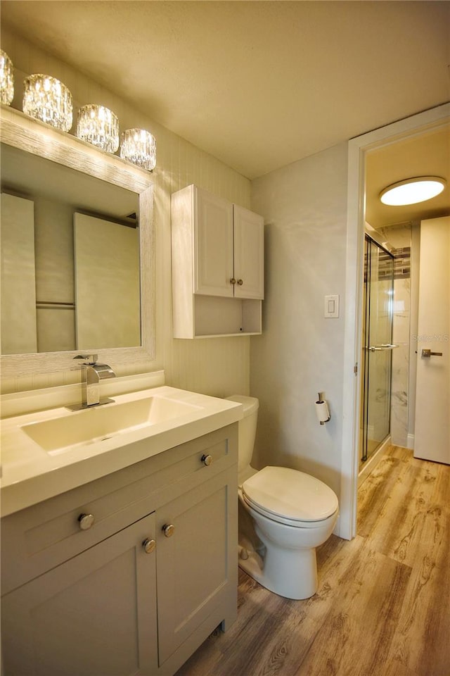 bathroom featuring hardwood / wood-style floors, toilet, a shower with door, and vanity