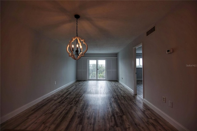 spare room featuring a notable chandelier and dark hardwood / wood-style flooring