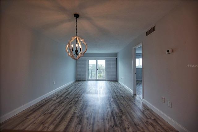 unfurnished room with dark wood-type flooring and a chandelier